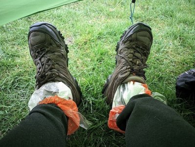 A person's feet in socks, with plastic bread bags pulled over them as waterproof liners.